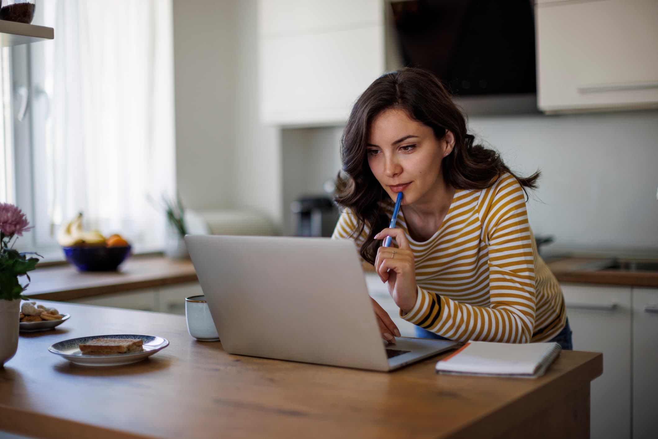 A woman seated at a table, focused on her laptop, engaged in her trading strategies