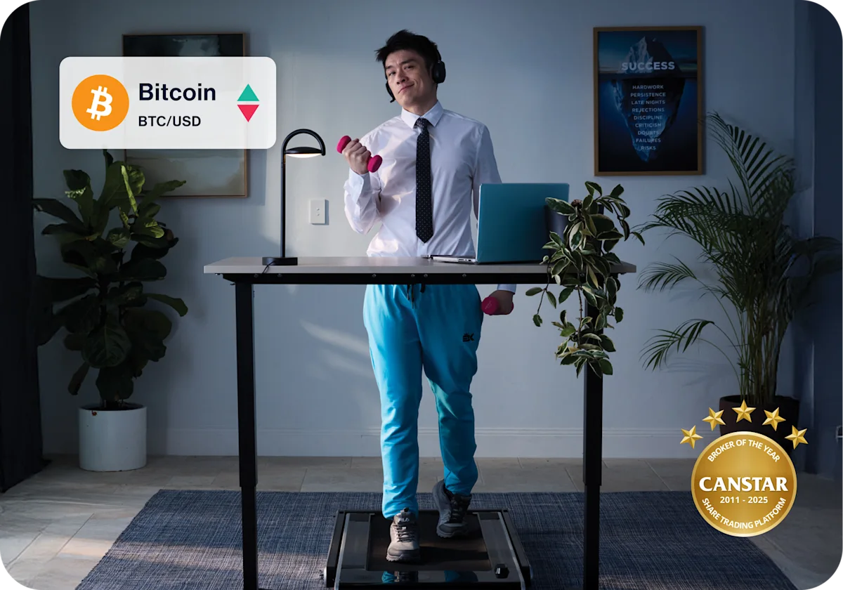 A man stands on a treadmill, using his laptop placed on a nearby surface to invest in shares